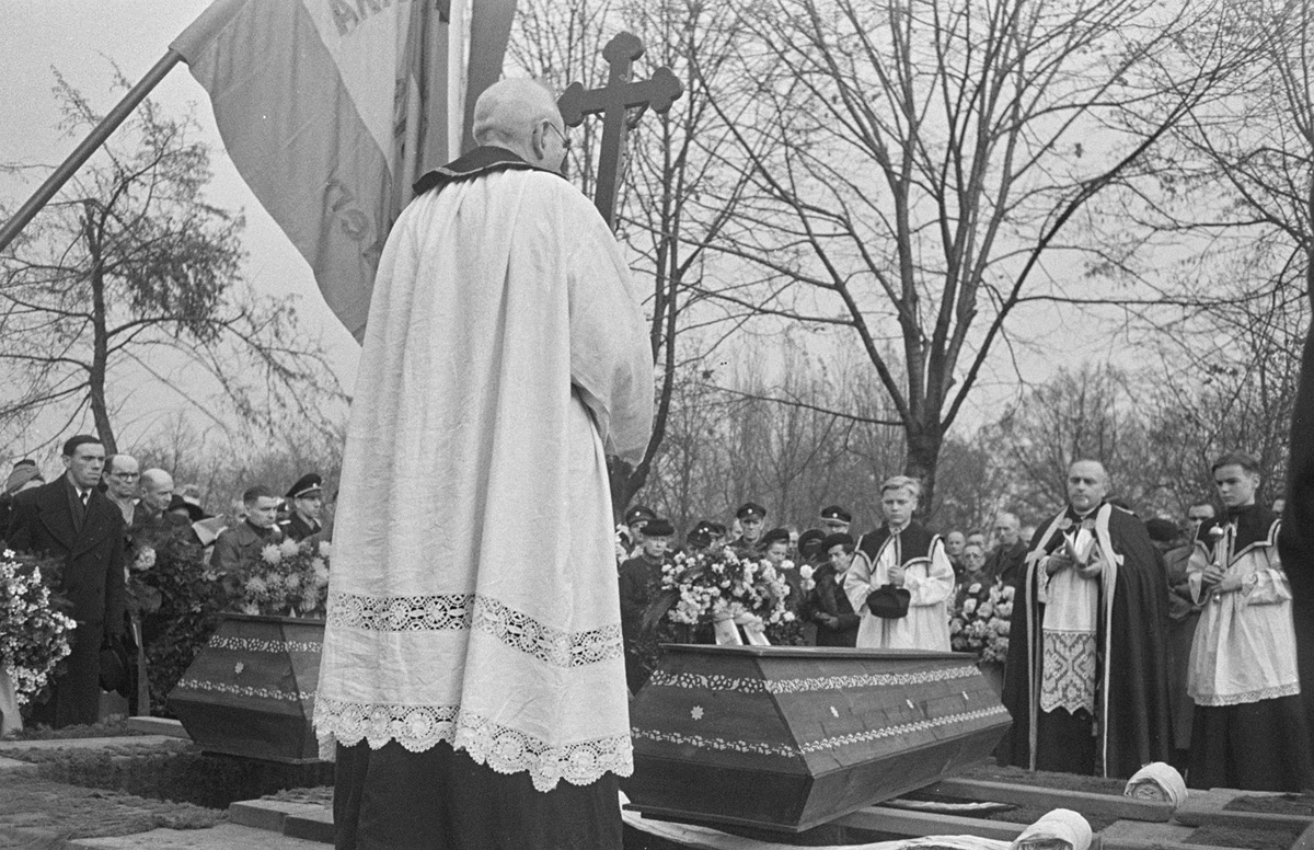 Pater Franz Bänsch, umrahmt von zwei Messdienern vor den drei Särgen am 3. November 1948
© SLUB/Deutsche Fotothek, Erich Höhne/Erich Pohl (Serie „Trauerfeier VVN“)